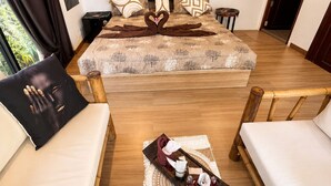 Een slaapkamer met een bed, twee fauteuils, een bijzettafeltje met dienblad en een schilderij aan de muur.