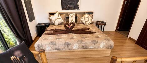 A bedroom with a bed, two armchairs, a coffee table with a tray, and a painting on the wall.