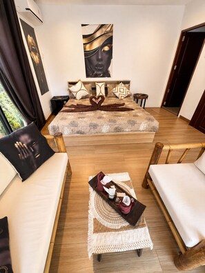 A bedroom with a bed, two armchairs, a coffee table with a tray, and a painting on the wall. - Bohemian-style 4-bedroom villa in Bali with private pool, sauna, and ice bath; beach just a 1-minute walk away (Surat Thani)