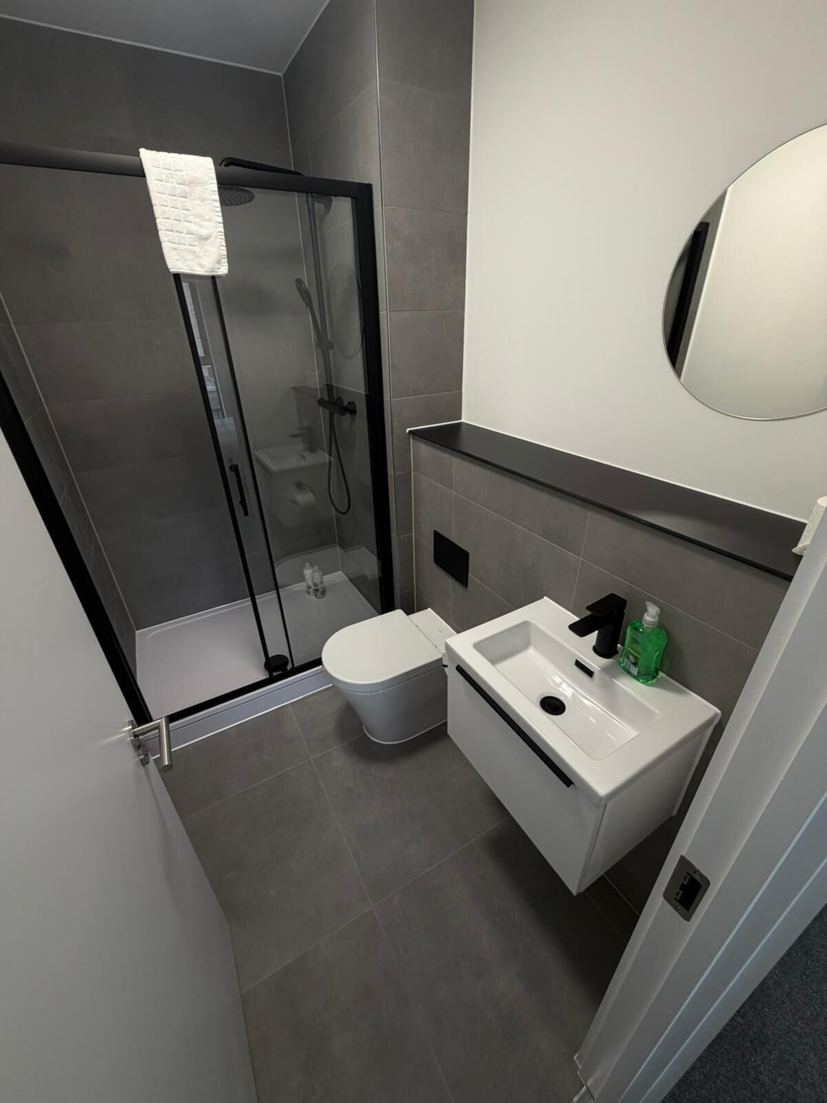 A modern bathroom with a glass shower enclosure, a white toilet, and a white sink with a mirror above it.