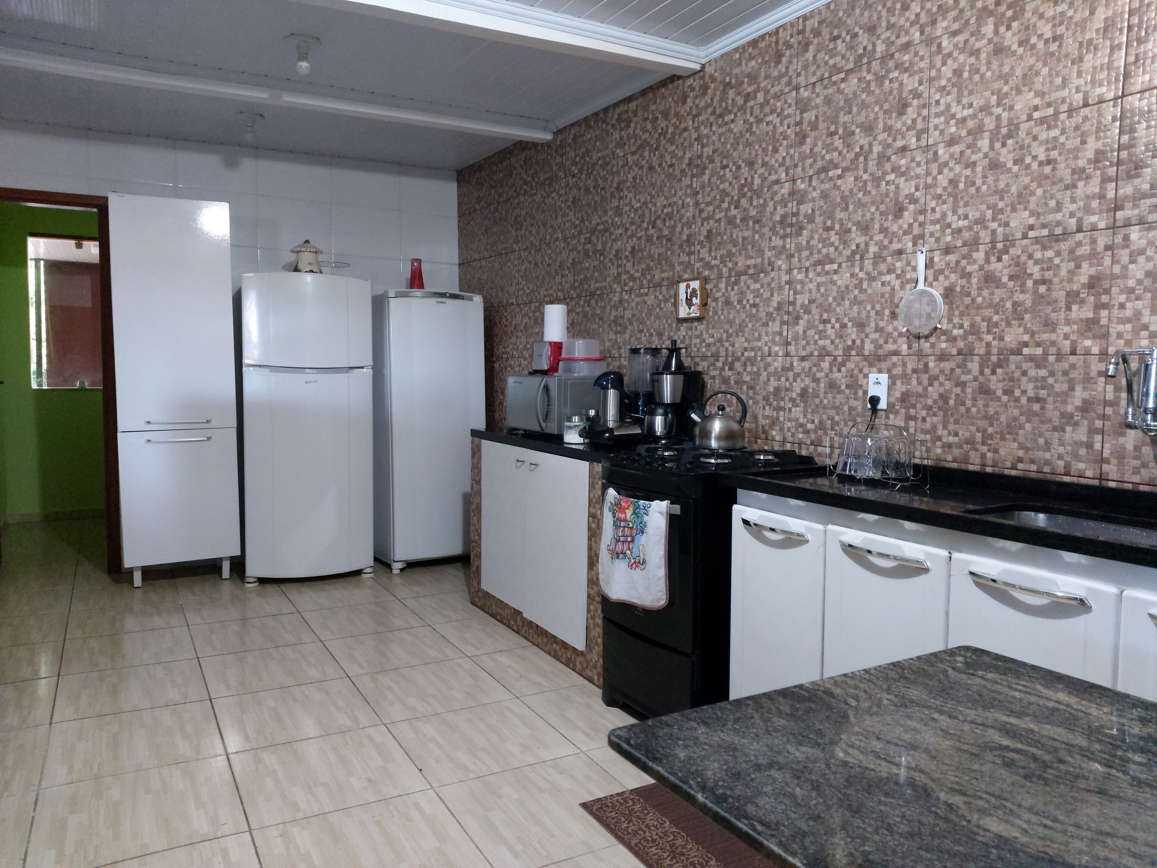 A kitchen with white cabinets, a black countertop, and a tiled backsplash.