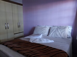 Une chambre à coucher avec un lit, une armoire et un mur violet.