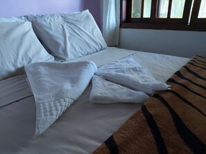 A bed with white linens and a striped blanket.