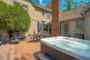 Eine Terrasse mit Gartenmöbeln, einem Whirlpool und einem Ziegelkamin.