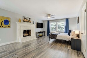 A bedroom with a fireplace, a bed, a TV, and a window with curtains. - Starsmore Manor! Walk to Broadmoor w/ Hot Tub (Colorado Springs)
