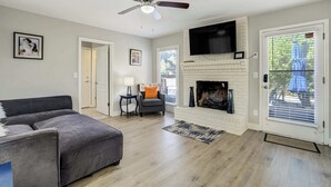 Ein Wohnzimmer mit grauem Sofa, Kamin, Fernseher darüber und Deckenventilator.