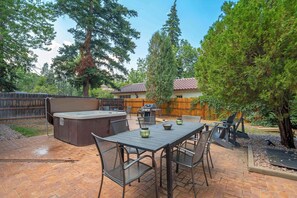 Eine Außenpatio mit Whirlpool, Grill und Essbereich.
