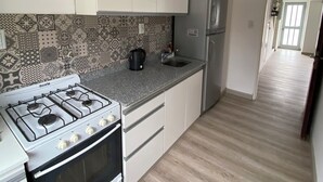 A kitchen with a gas stove, oven, refrigerator, and patterned backsplash.