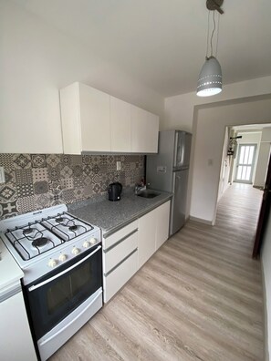 A kitchen with a gas stove, oven, refrigerator, and patterned backsplash.