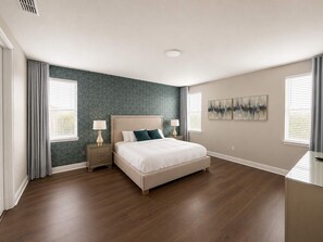 A bedroom with a bed, nightstands, a wall with artwork, and a window with curtains. - Onyx Villa Luxury 12 Bed Home 9 Mins to Disney World (Kissimmee)