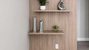 Una mensola a muro in legno con oggetti decorativi e una pianta in vaso.