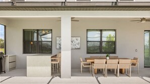 A modern outdoor patio with a pool, a dining area with wicker furniture, and a grill. - The Premiere House - 8 Mins to Universal Studios 3 Mins to Sea World 15 Mins to Disney World (Orlando)
