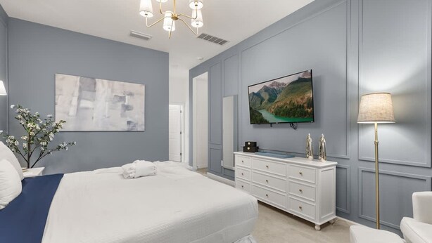A bedroom with a large bed, a dresser, a television, and a lamp. - The Premiere House - 8 Mins to Universal Studios 3 Mins to Sea World 15 Mins to Disney World (Orlando)