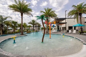 A swimming pool with palm trees, a water slide, and a building with outdoor seating. - The Premiere House - 8 Mins to Universal Studios 3 Mins to Sea World 15 Mins to Disney World (Orlando)