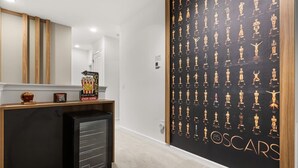 A hallway with a black wall featuring a pattern of golden statuettes, a popcorn machine, and a sign indicating a cinema. - The Premiere House - 8 Mins to Universal Studios 3 Mins to Sea World 15 Mins to Disney World (Orlando)