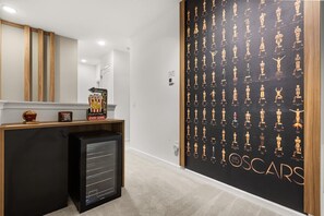A hallway with a black wall featuring a pattern of golden statuettes, a popcorn machine, and a sign indicating a cinema. - The Premiere House - 8 Mins to Universal Studios 3 Mins to Sea World 15 Mins to Disney World (Orlando)