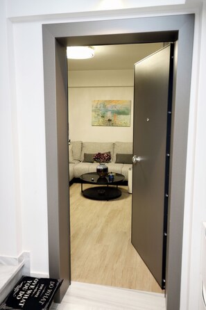 A doorway leading to a living room with a sofa, a coffee table, and a painting on the wall. - Luxury Athens Duplex with Acropolis View, Private Heated Jacuzzi & Parking (Athina)