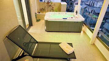 Un balcon avec un espace salon, un jacuzzi et une vue sur la ville.