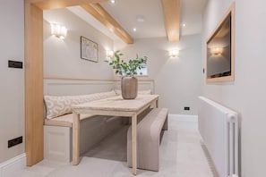 A room with a bench, a table, a potted plant, a wall-mounted TV, and recessed lighting. - Easter Crag, 3 bedroomed luxury escape with hot tub (Bowness-on-Windermere)