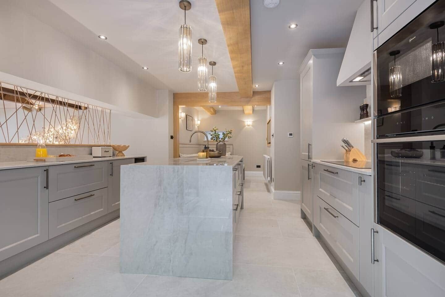 A modern kitchen with a central island, grey cabinetry, and pendant lighting.