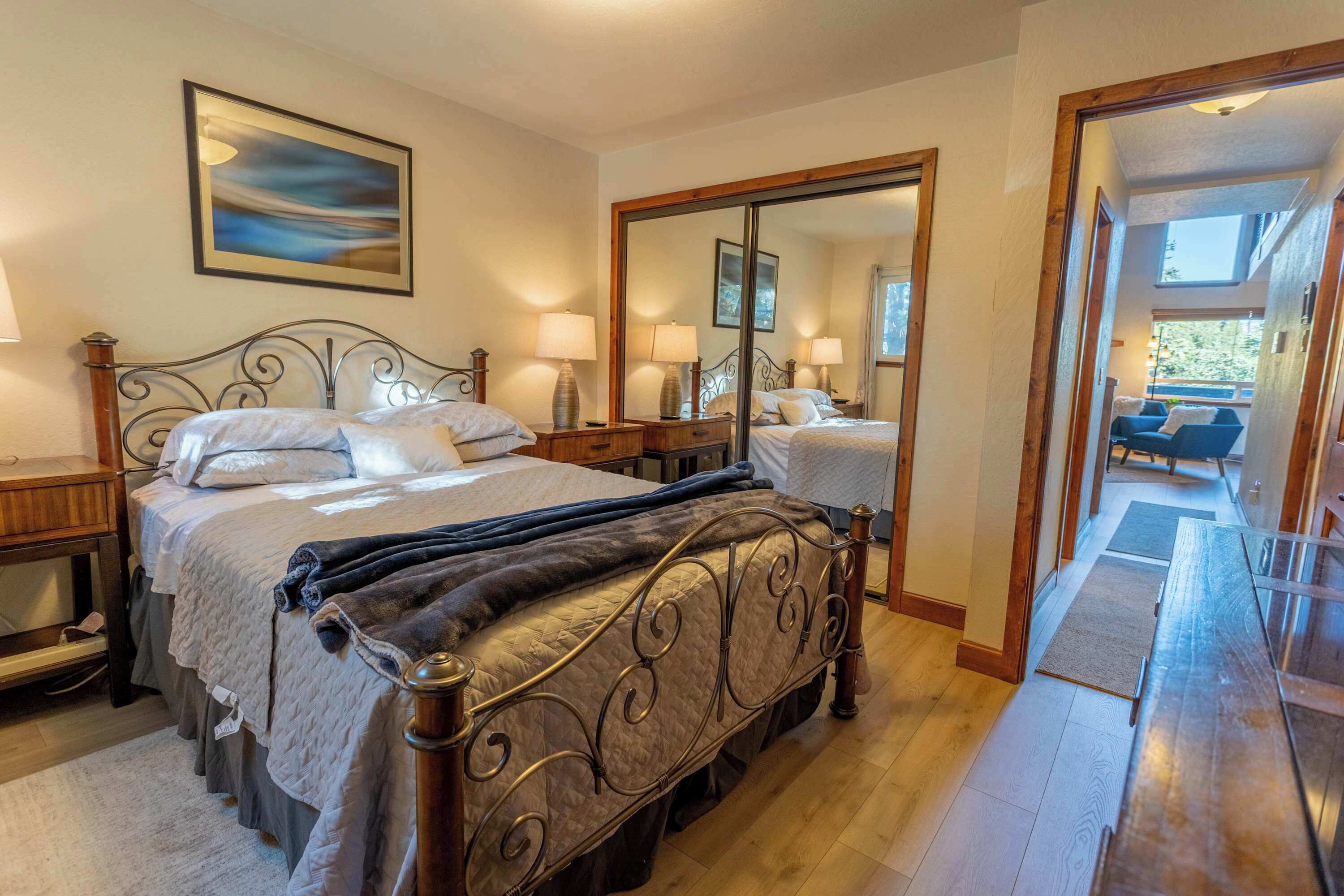 Una camera da letto luminosa con un letto grande, comodini, uno specchio e un quadro appeso al muro.