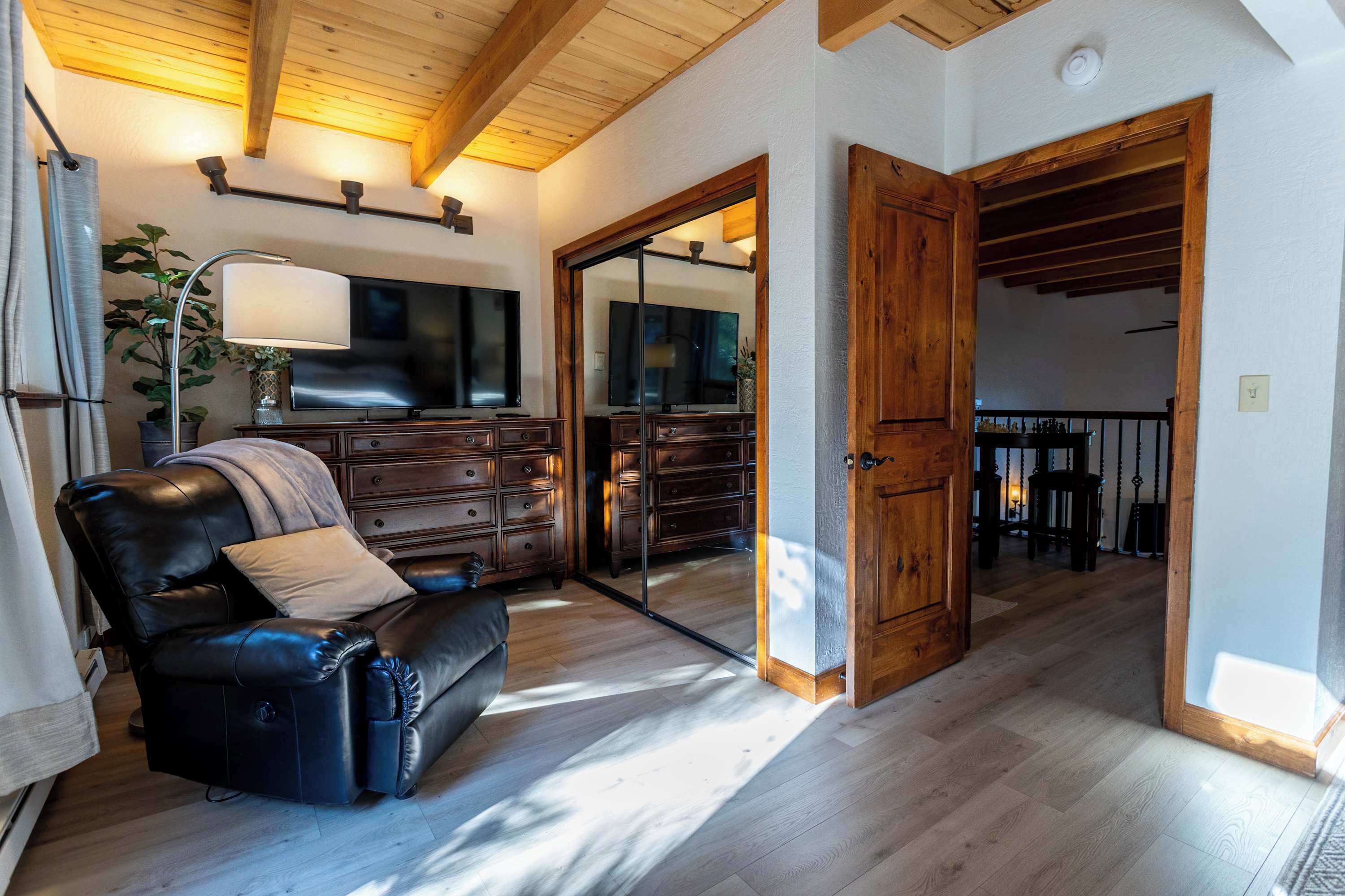 Un salon avec un canapé en cuir, des meubles en bois, un téléviseur et un escalier menant à un autre niveau.