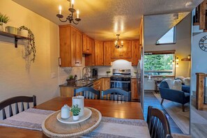 A modern kitchen with wooden cabinets, a built-in oven, and a dining area with a wooden table and chairs. - Heavenly Vista Lago Lake View - Luxury Ski-In-Ski-Out Retreat with Stunning Lake Views (Stateline)