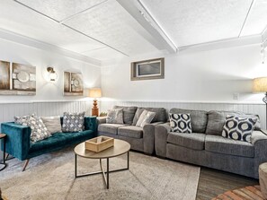 Un salon avec un canapé turquoise, un canapé gris et une table basse ronde.