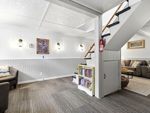 Un vaste espace de vie comprenant une bibliothèque, un canapé et un escalier.