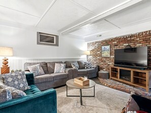 Ein Wohnzimmer mit einer Couch, einem Couchtisch und einem Fernseher an einer Ziegelwand.