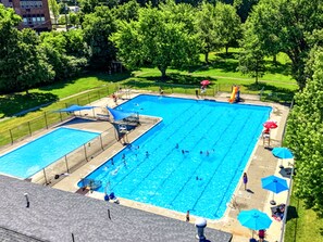 Une piscine dotée d’un plongeoir et de toboggans, entourée d’arbres et bordée d’une pelouse.