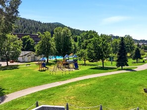 Ein Park mit Spielgeräten, einem Fußweg und Bäumen.