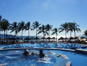 A swimming pool with palm trees and umbrellas, surrounded by lounge chairs. - APARTMENT IN THE HEART OF MANZANILLO, COLIMA (Manzanillo)