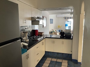 A kitchen with white cabinets, a black countertop, and a tiled floor. - APARTMENT IN THE HEART OF MANZANILLO, COLIMA (Manzanillo)