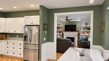 A modern kitchen with white cabinetry, a stainless steel refrigerator, and a marble island.