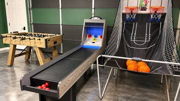 A recreational area with a foosball table, a bowling alley, and a basketball hoop.