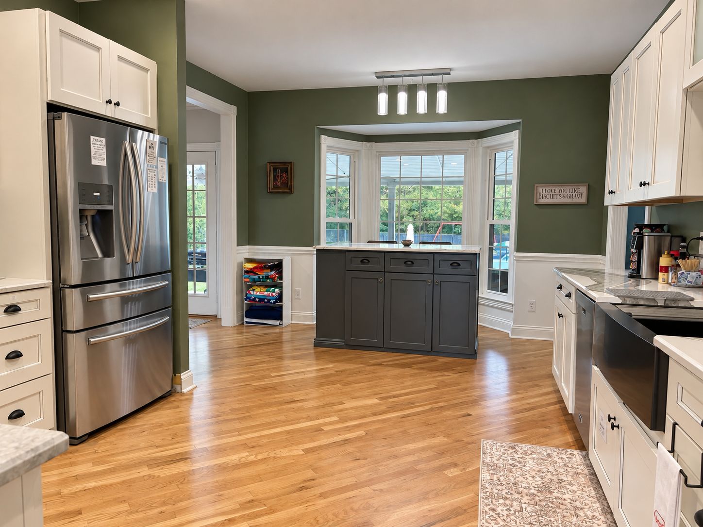 A kitchen with a stainless steel refrigerator, a built-in oven, and a dark gray island with a sink.