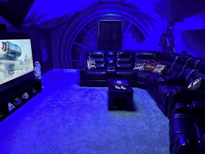 A room with a curved ceiling, a large screen, leather seating, and a Star Wars figure. - Country Getaway with Private Hot Tub, Pool, Game Rooms, & Star Wars Theater! (Portland)
