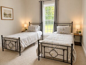 A bedroom with two beds, a window, and a bedside table with a lamp. - Country Getaway with Private Hot Tub, Pool, Game Rooms, & Star Wars Theater! (Portland)