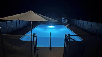 Piscina com toldo e cerca.