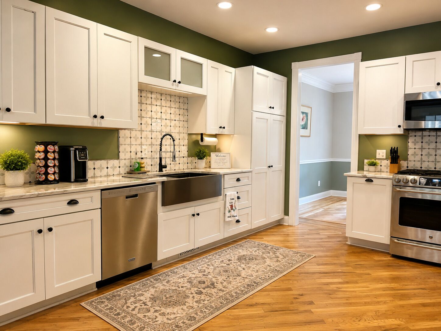 A kitchen with white cabinets, stainless steel appliances, a coffee maker, and a rug.