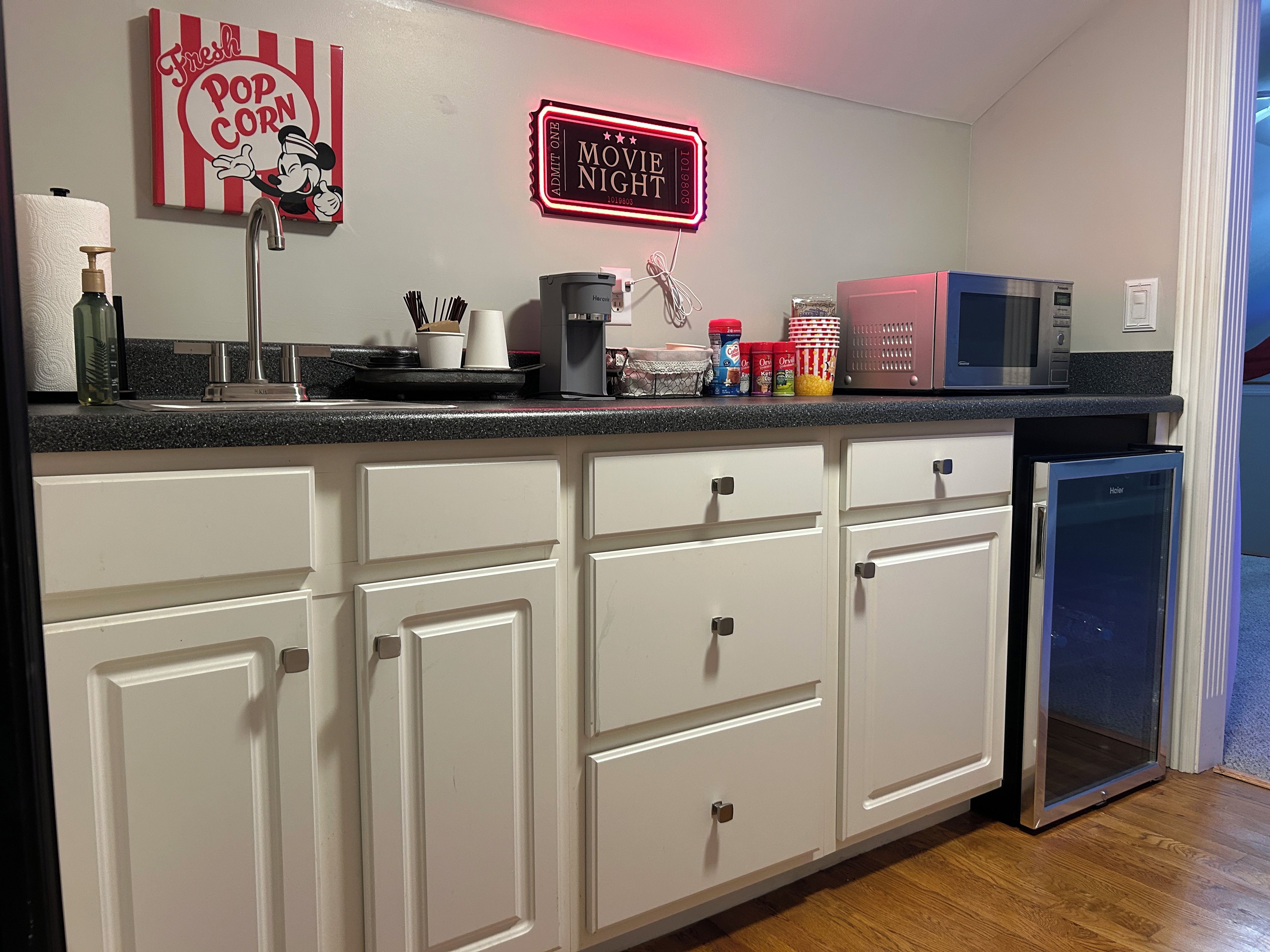 A kitchen with white cabinets, a microwave, a toaster, and a refrigerator.