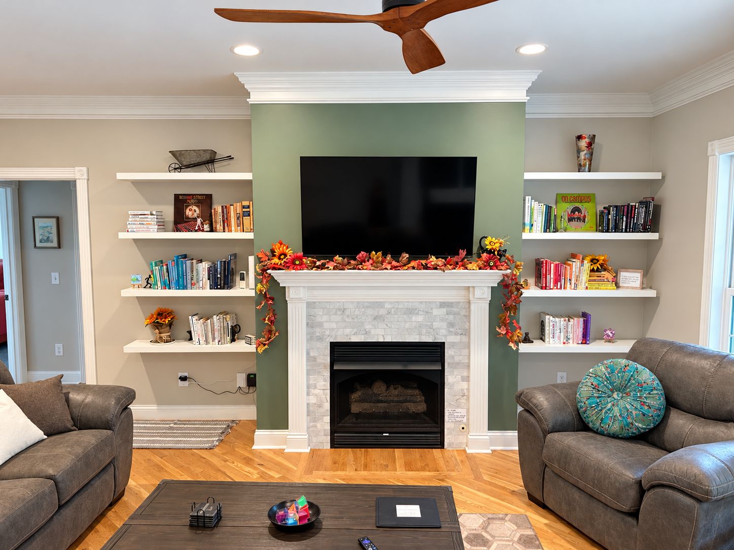 A living room with a fireplace, bookshelves, a television, and two leather sofas.
