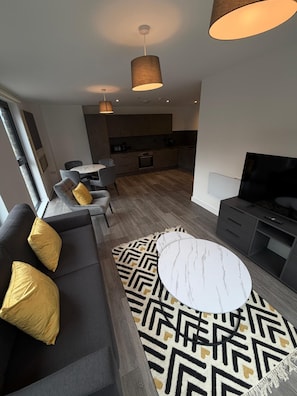 Ein modernes Wohnzimmer mit einer Couch, einem Couchtisch und einem Fernseher.
