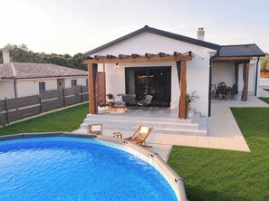 Ein modernes Haus mit Swimmingpool, Terrassenmöbeln und einer überdachten Außenbereich.
