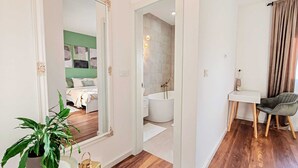 Et moderne hotelværelse med et stort spejl, en seng, et badeværelse med badekar og et skrivebord med stol.