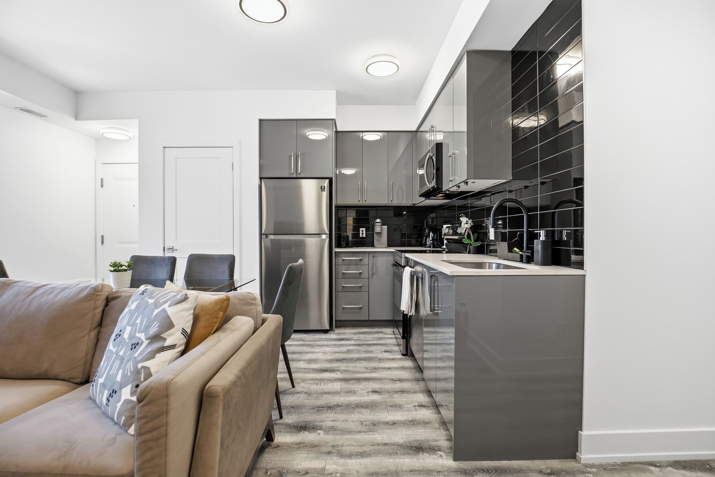 A modern kitchen with stainless steel appliances, a built-in oven, and a large island with a sink.