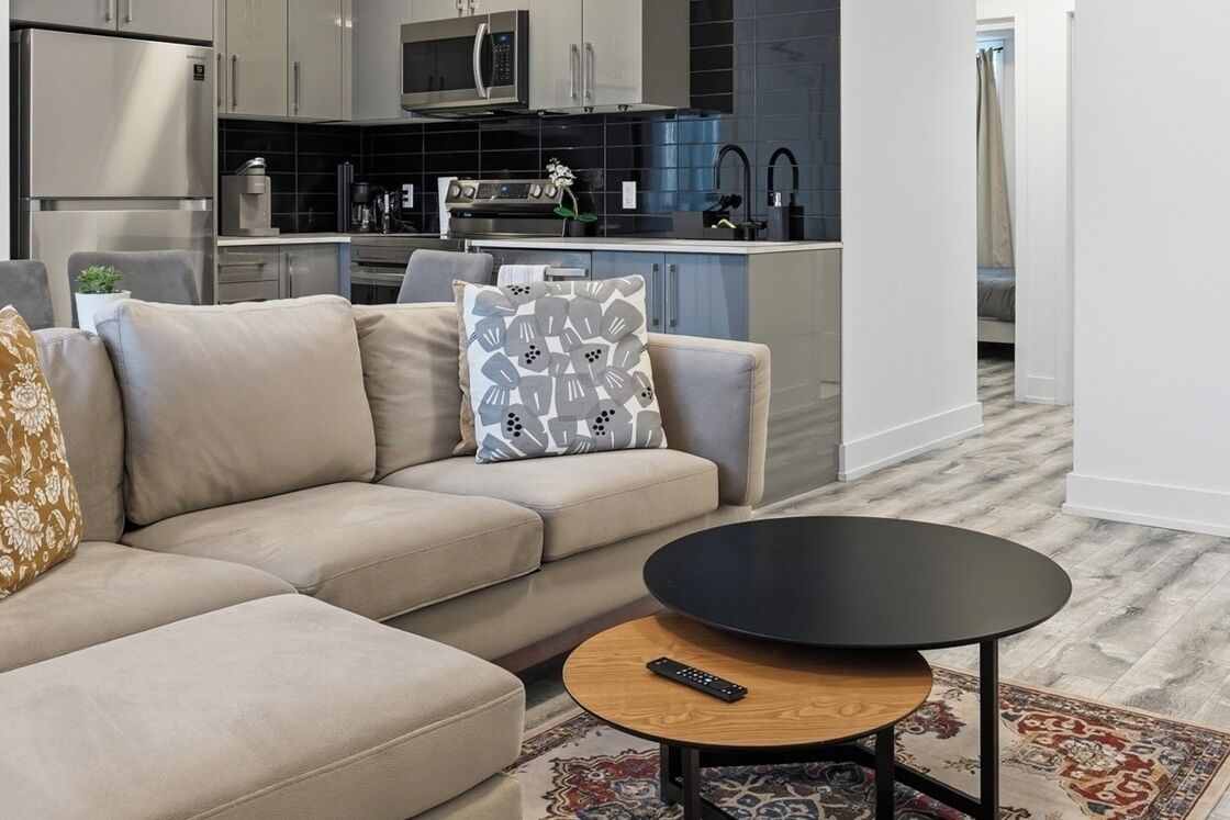A modern living room with a sofa, a round coffee table, and a remote control on it.