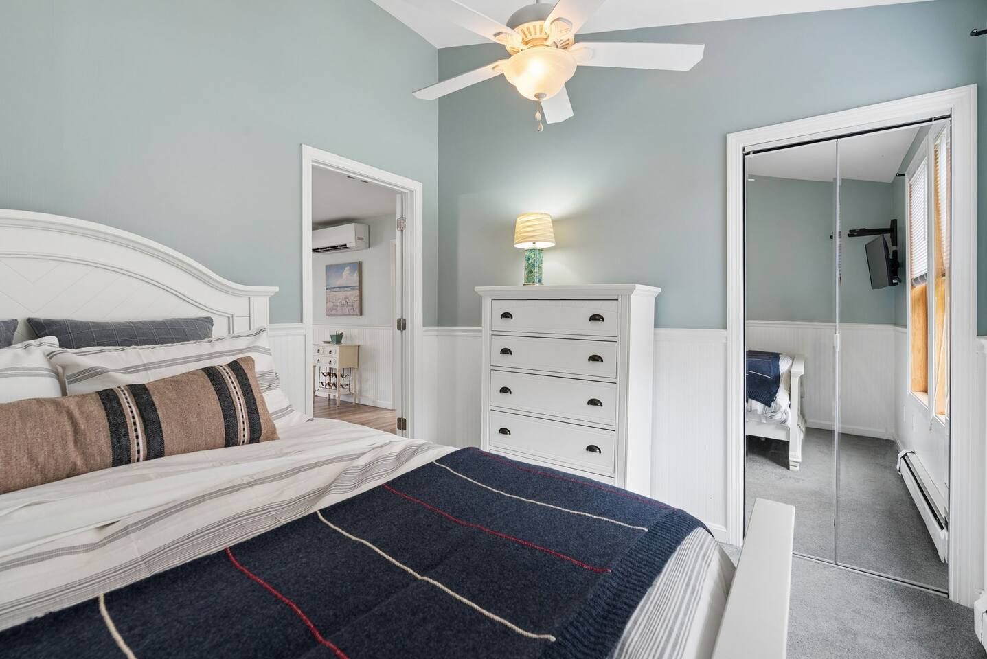 Un dormitorio con cama, cómoda, ventilador de techo y espejo.