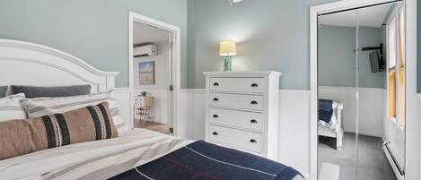 Un dormitorio con cama, cómoda, ventilador de techo y espejo.